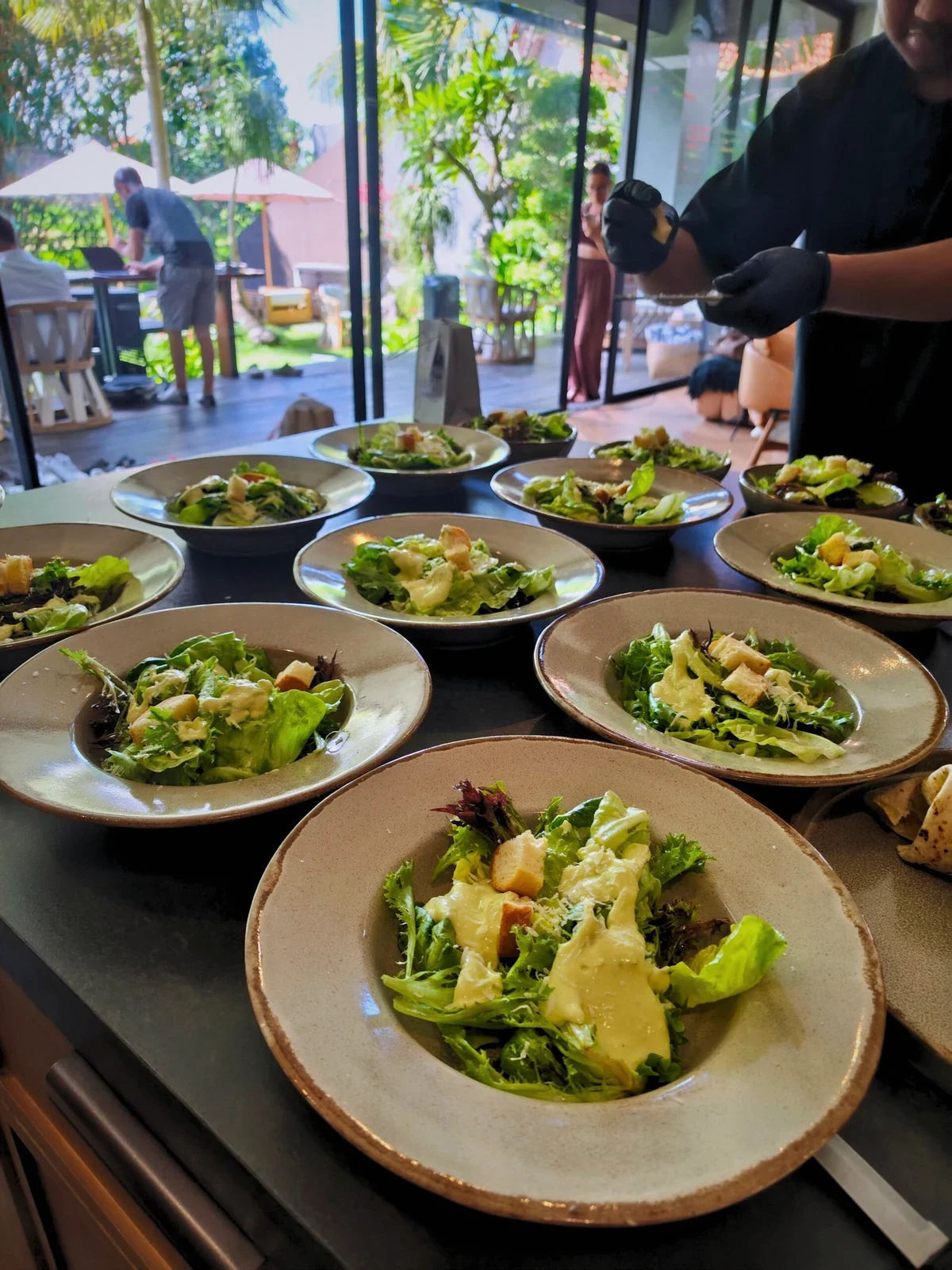 A chef finishing plates of salad beside a villa dining table
