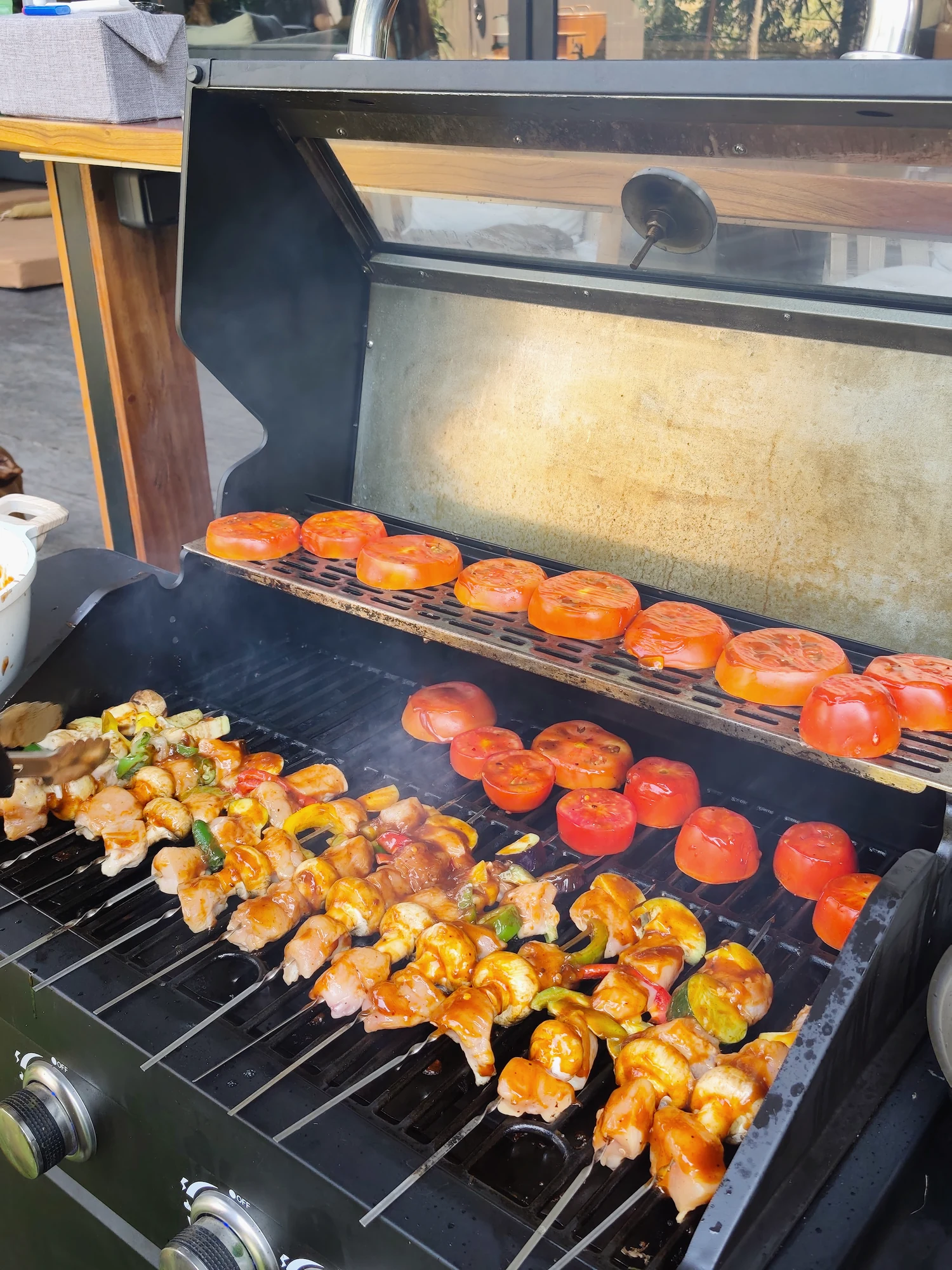 Skewers and tomatoes cooking on a villa barbecue