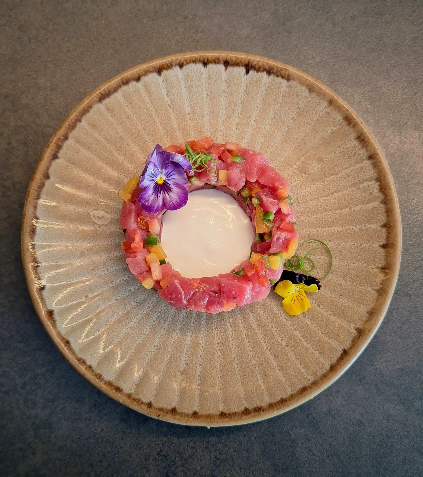 Fish tartare with edible flowers and a pale sauce