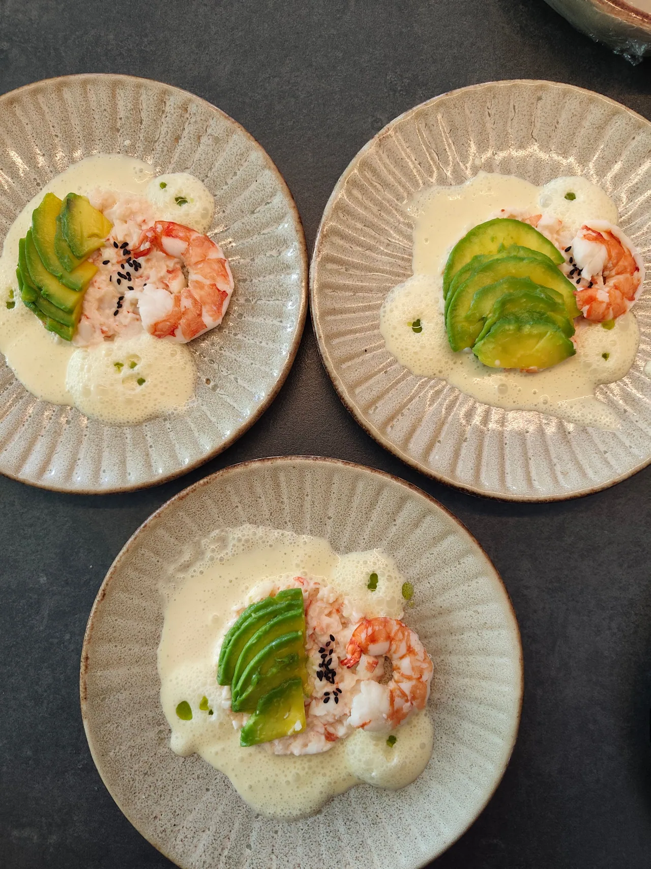 Prawns and sliced avocado with a pale sauce on ceramic plates