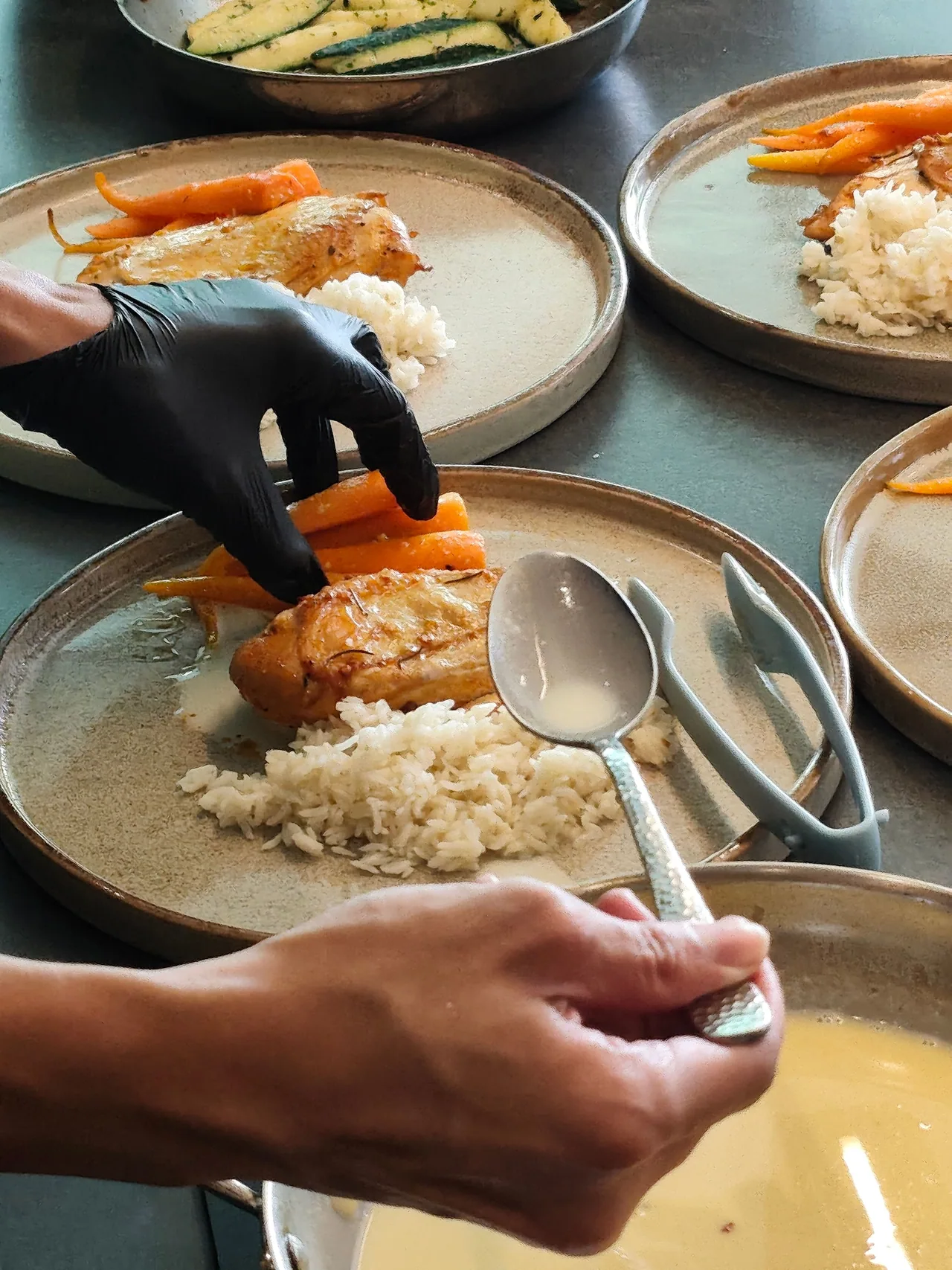 A chef arranging carrots beside chicken and rice on plates