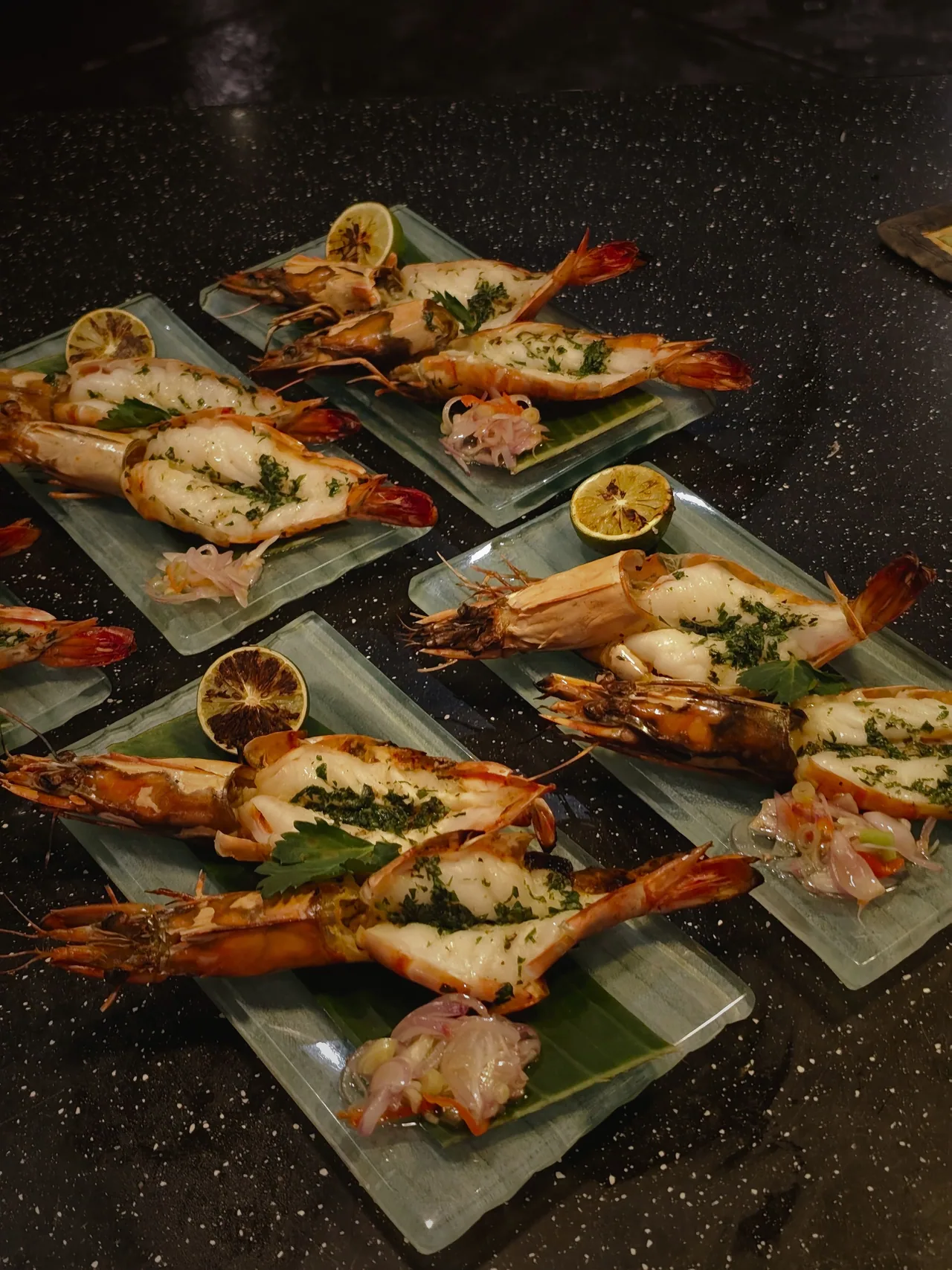 Grilled prawns with herbs and charred lemon on glass plates