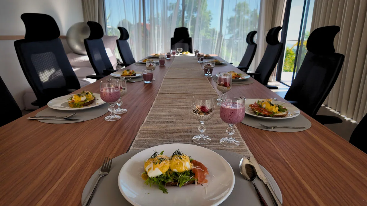 A long villa table set with breakfast plates and fruit drinks